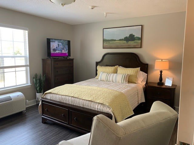 Cozy bedroom with a bed, lamp, and television.