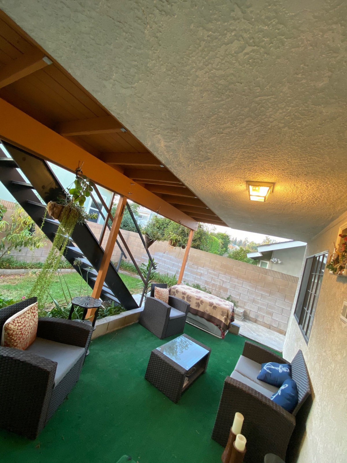 A cozy patio with outdoor furniture and stairs leading to the garden.