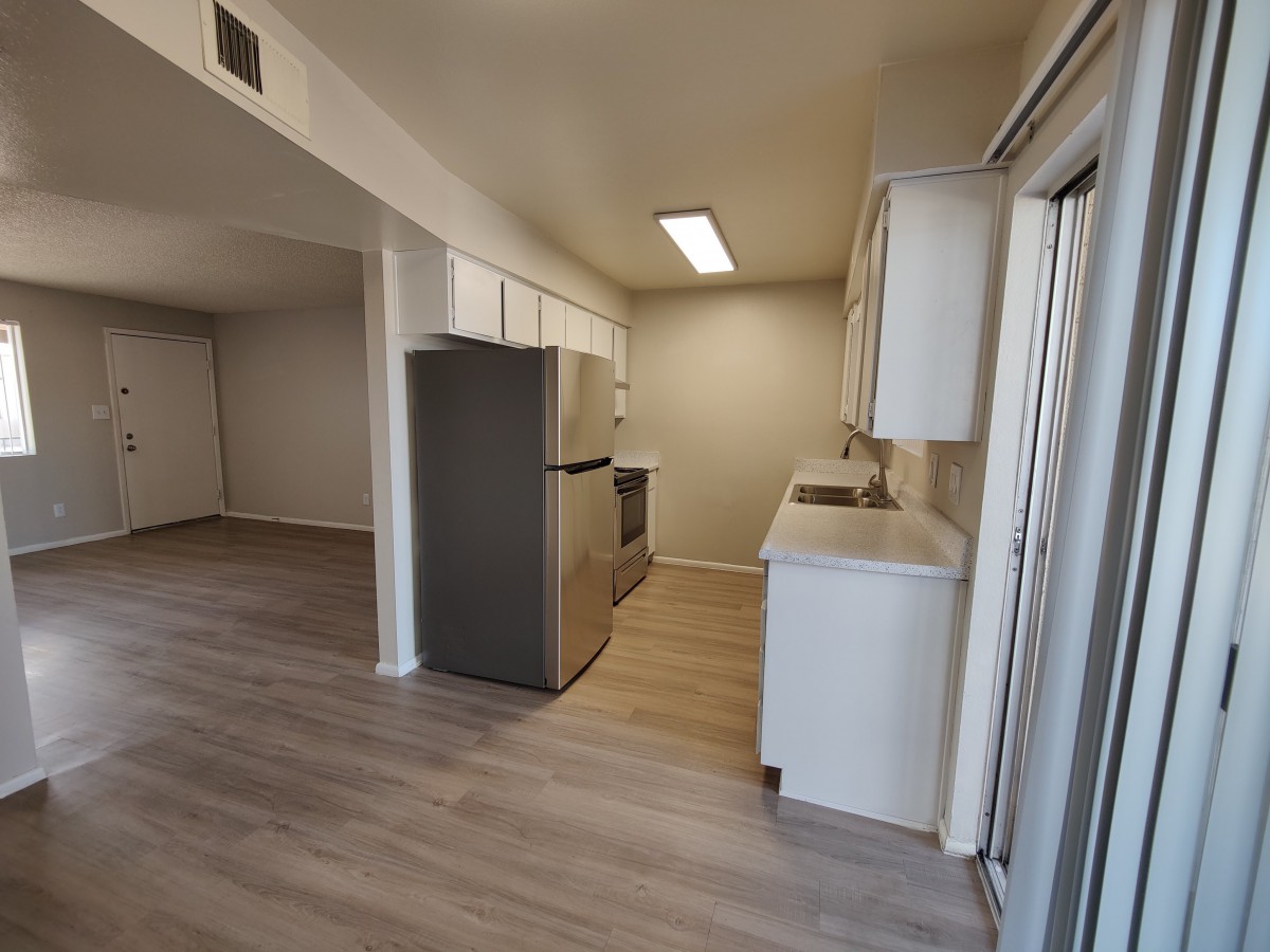 A modern apartment kitchen with white cabinets and stainless steel appliances.