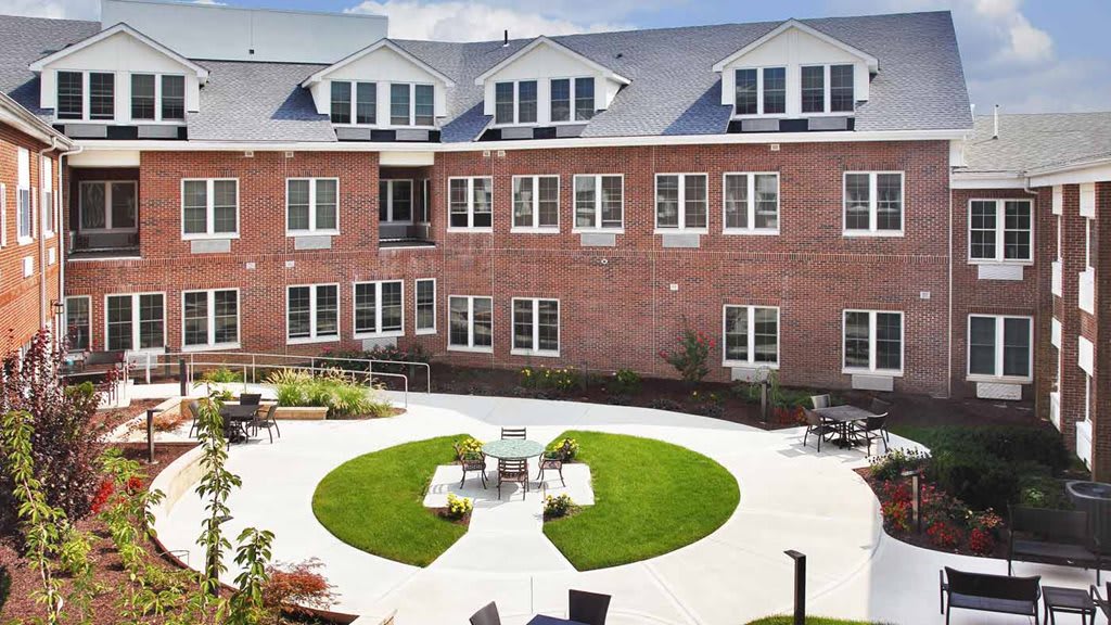 A view of a brick building with a courtyard featuring outdoor seating and a well-maintained lawn.