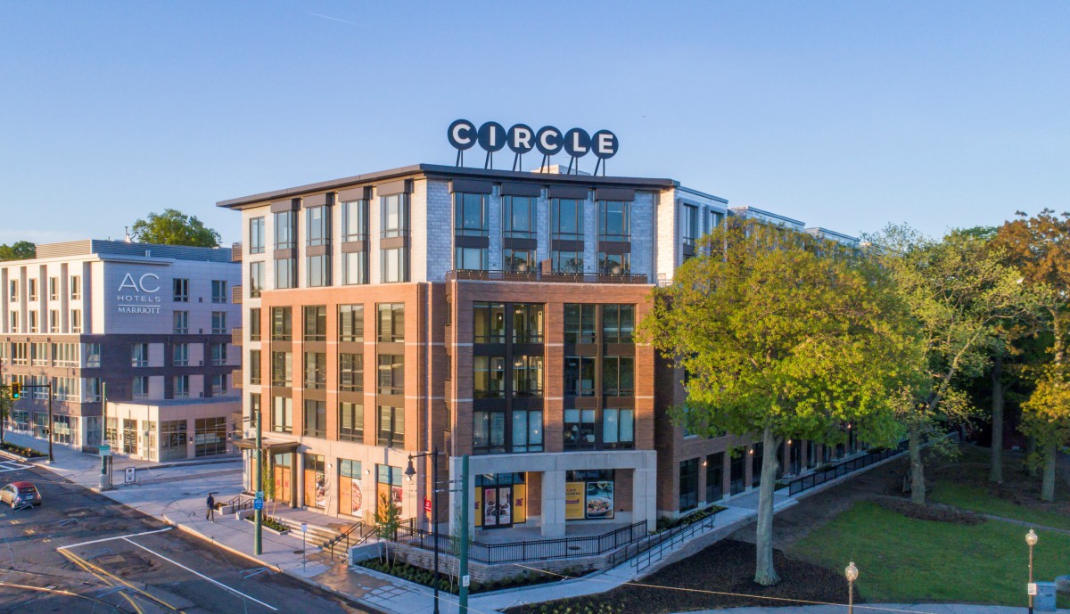 Modern office building with a glass facade and surrounding trees.