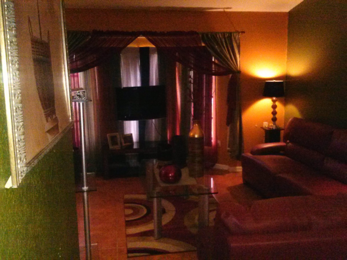 A warmly lit living room featuring a sofa, television, and elegant curtains.