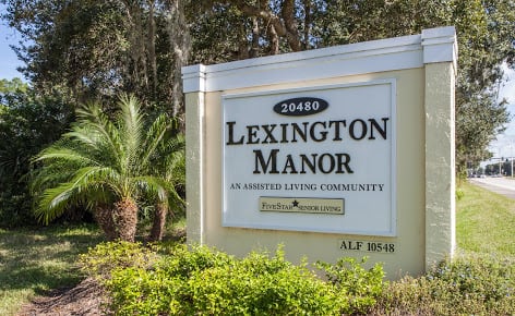 Sign for Lexington Manor Assisted Living Community surrounded by greenery.