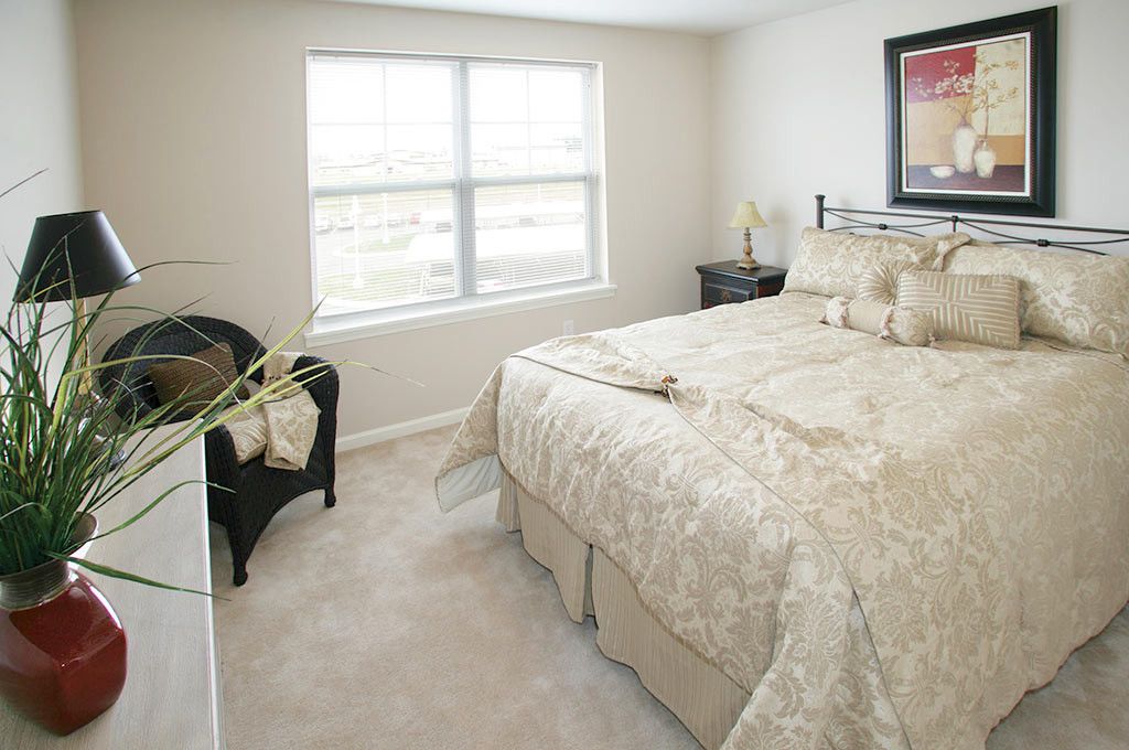 A cozy bedroom with a neatly made bed and natural light coming through the window.