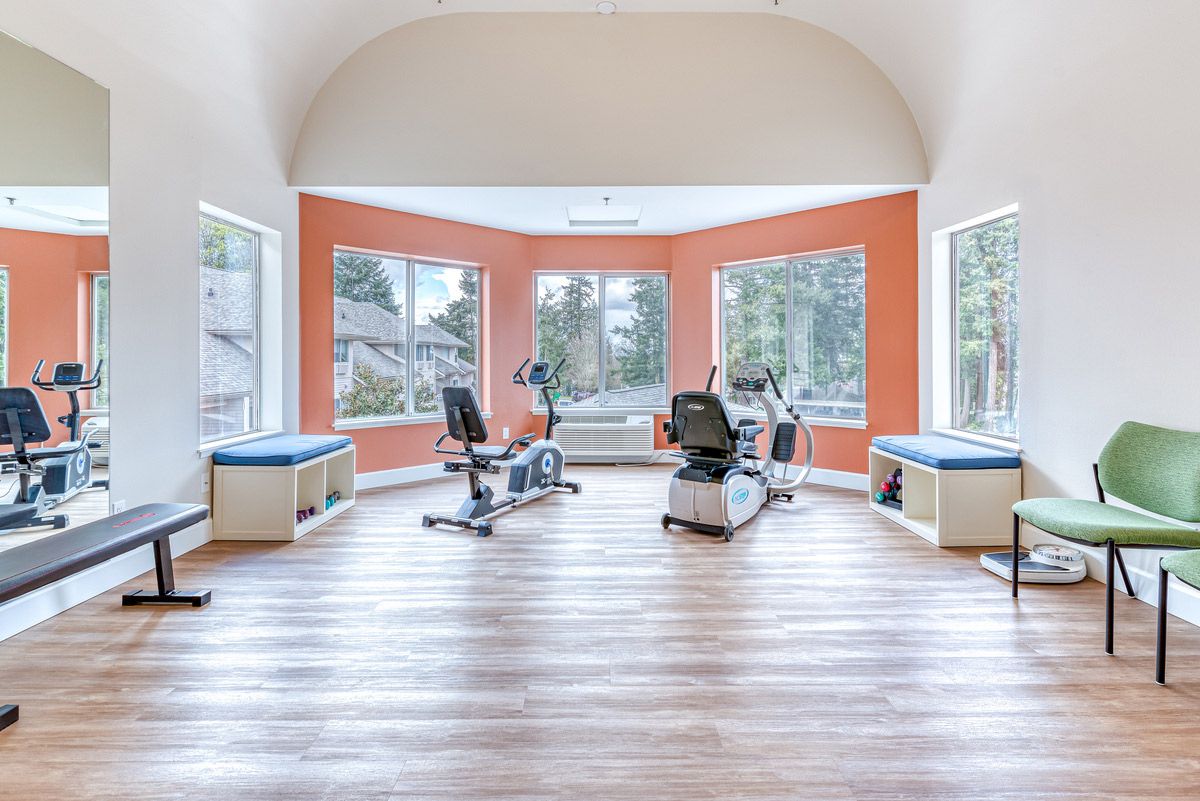 A bright and spacious gym with exercise equipment and large windows.