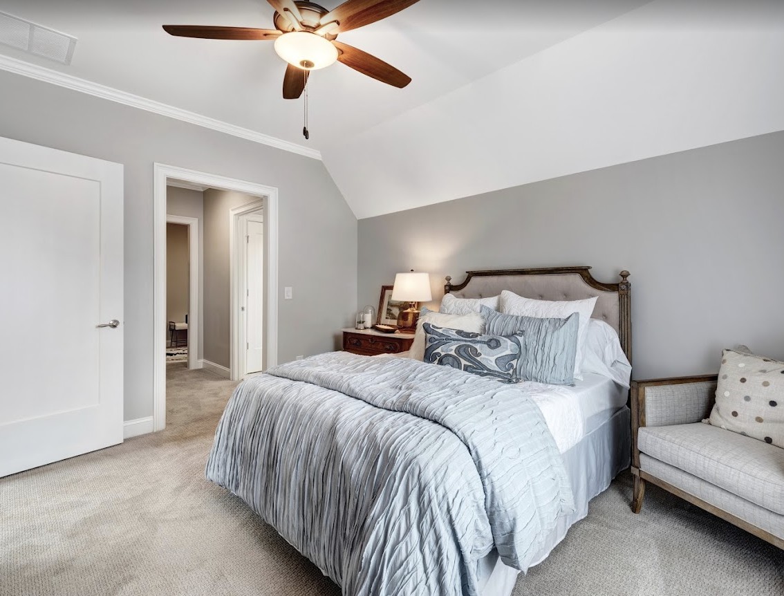 A cozy bedroom with a bed, nightstand, and ceiling fan.