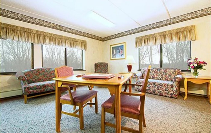A cozy meeting room with a wooden table, chairs, and sofas by the windows.