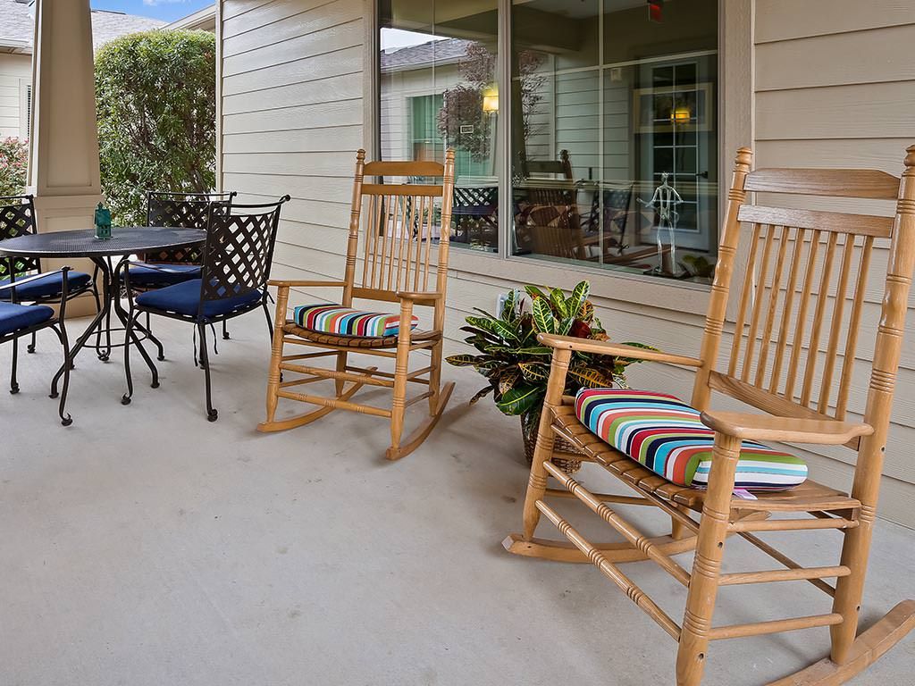 A cozy porch with wooden rocking chairs and a small table set, perfect for relaxing outdoors.