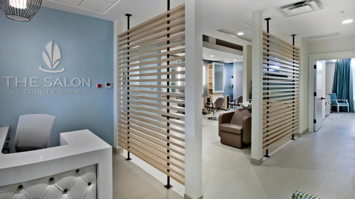 A modern salon interior featuring a waiting area with wooden partitions and comfortable seating.