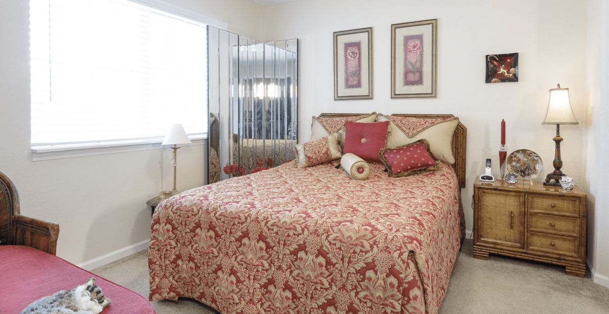 A cozy bedroom with a patterned bedspread, decorative pillows, and artwork on the walls.