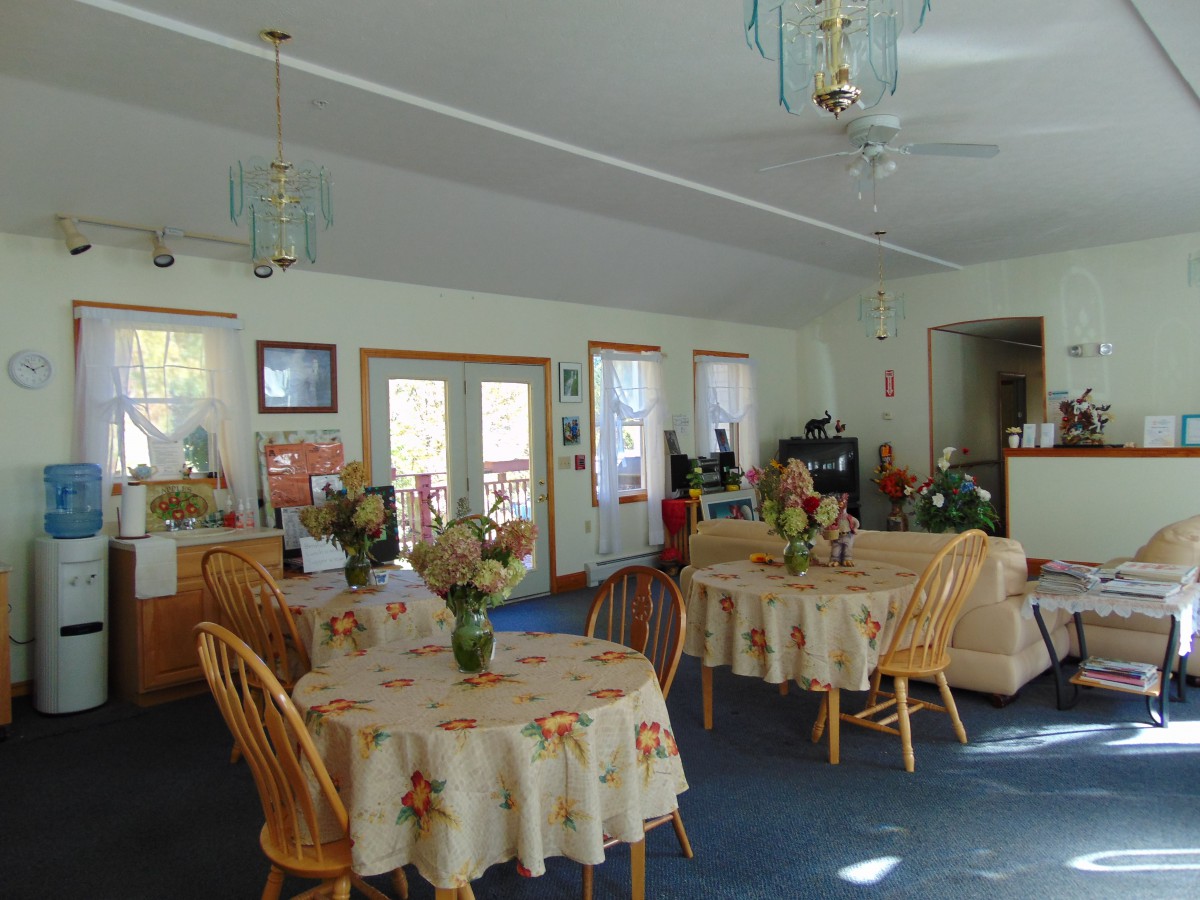 A cozy dining area with round tables and chairs, featuring decorative lighting and flowers on the tables.