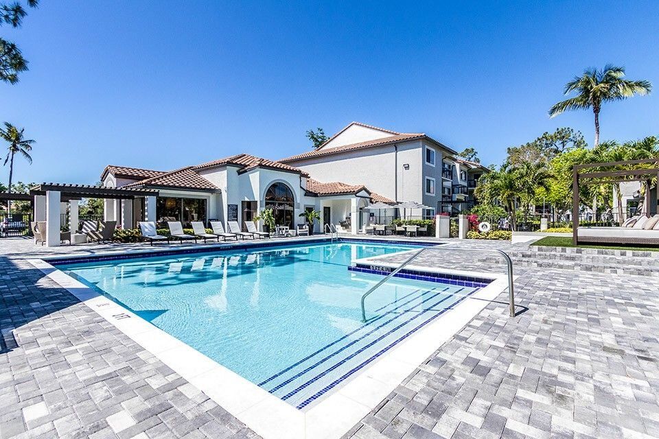A luxurious outdoor swimming pool next to a residential building on a sunny day.