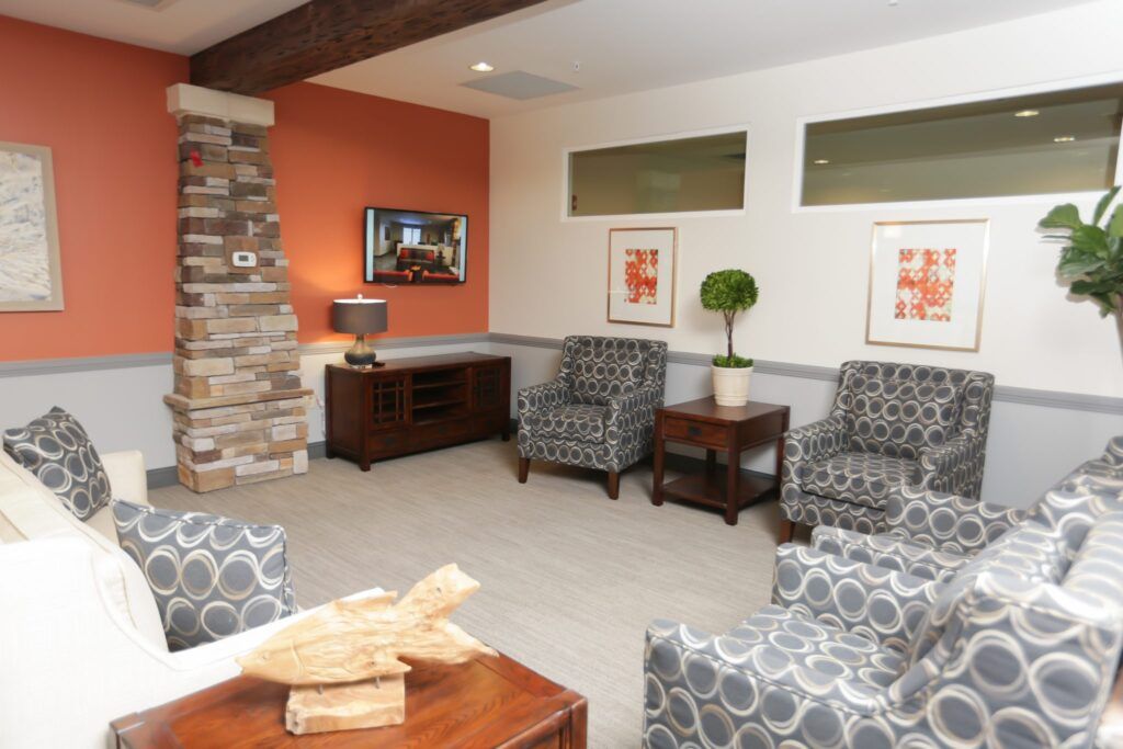 A modern living room featuring armchairs, a stone fireplace, and orange accent walls.