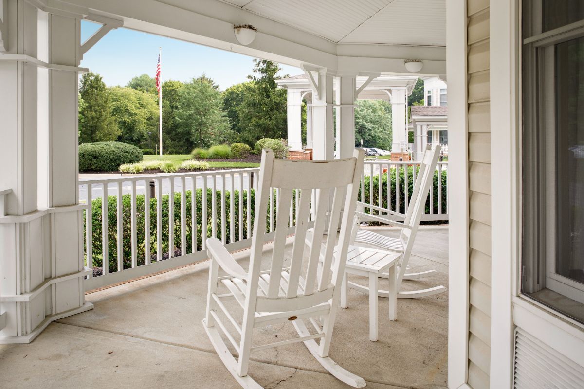 A serene porch with white rocking chairs overlooking a lush garden.