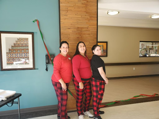 Three women dressed in festive attire pose together in a cheerful indoor environment.
