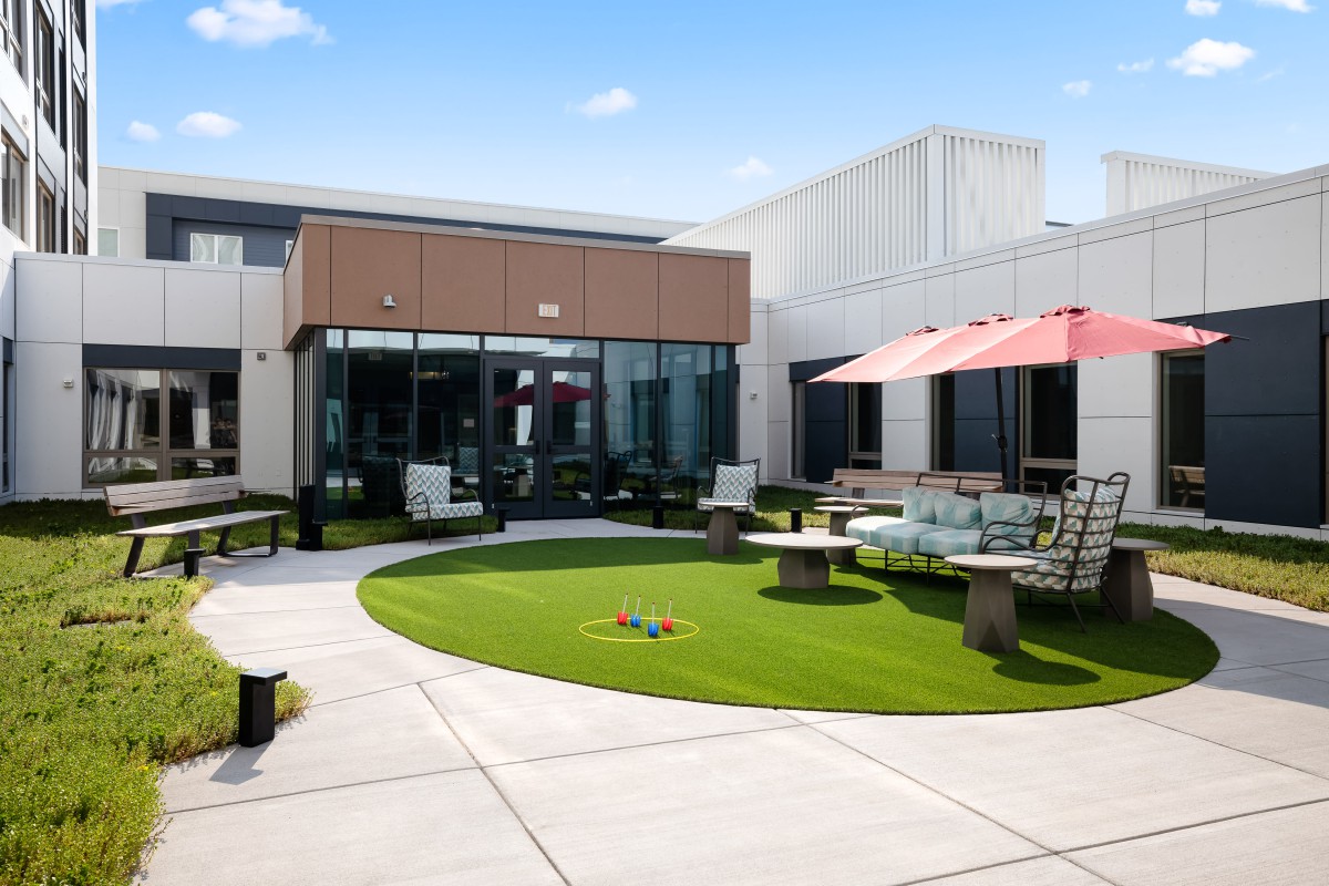 A modern outdoor patio with seating areas and a small lawn on a sunny day.