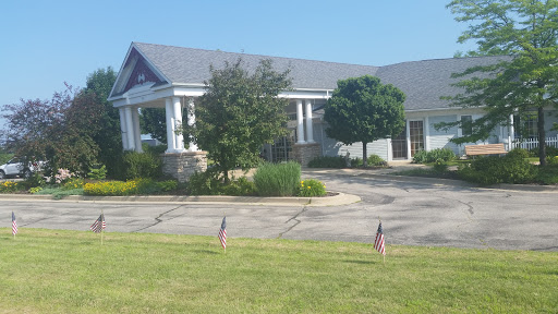 A peaceful view of a well-maintained building surrounded by greenery and small flags.