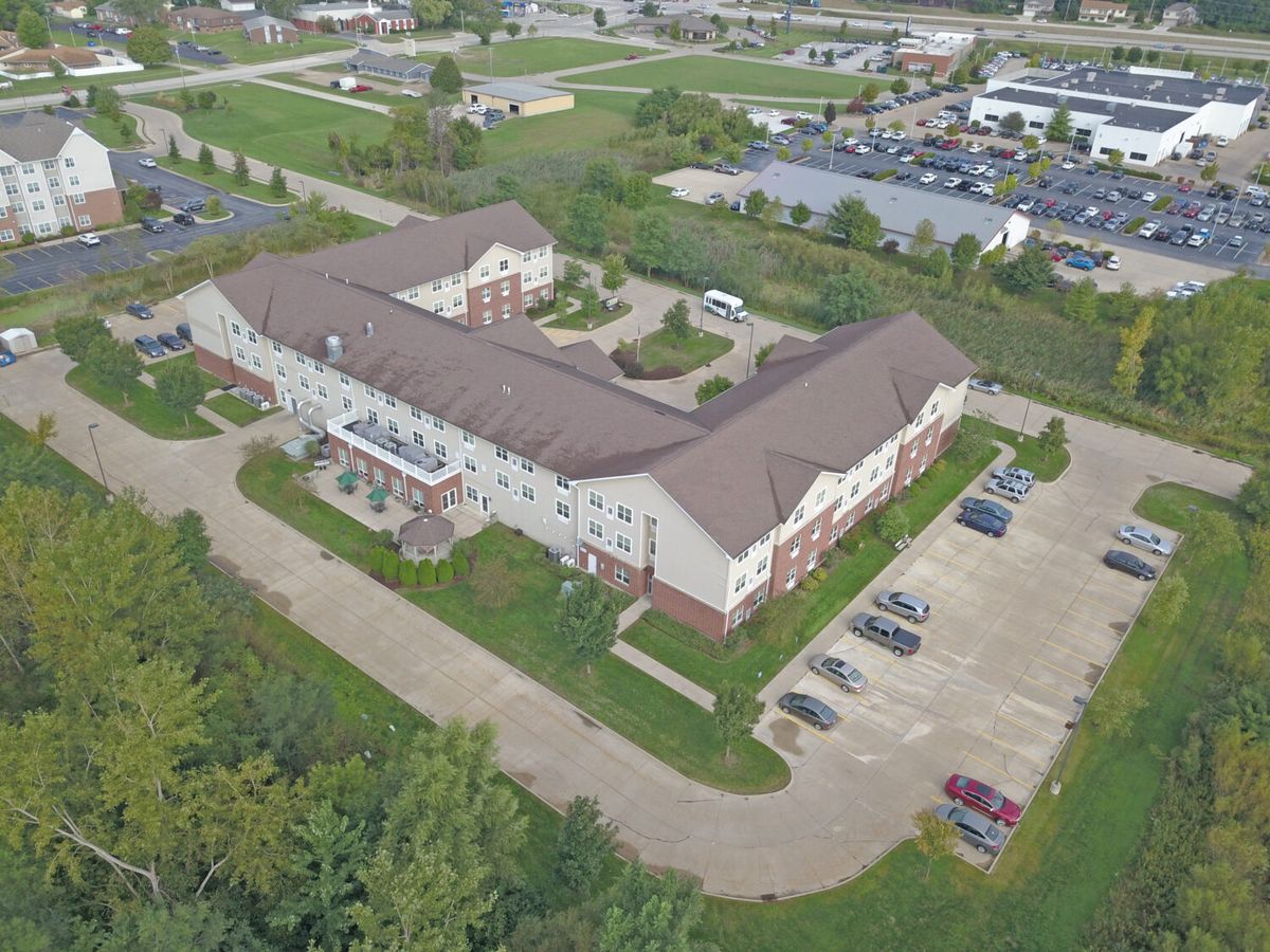 Aerial view of a large building with adjacent parking lot surrounded by greenery.