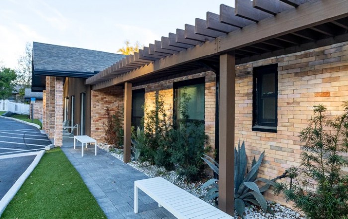 A modern brick building with a pergola and landscaped outdoor area.