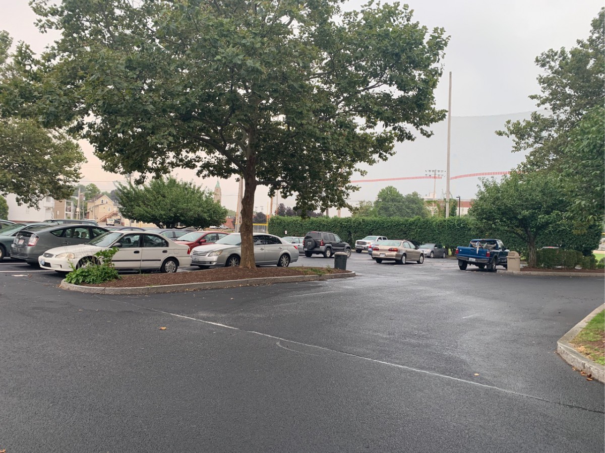 A parking lot with several cars under overcast skies.