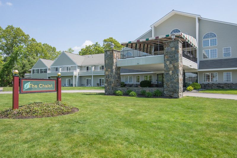 A well-maintained hotel with stone columns and a lush green lawn.