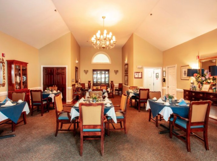An elegant dining room with neatly arranged tables and chairs under a chandelier.