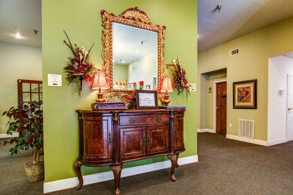 A traditional interior design featuring a wooden sideboard and ornate mirror against green walls.