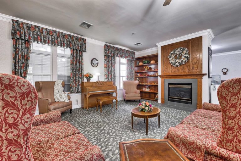A cozy living room featuring a piano, fireplace, and comfortable seating.