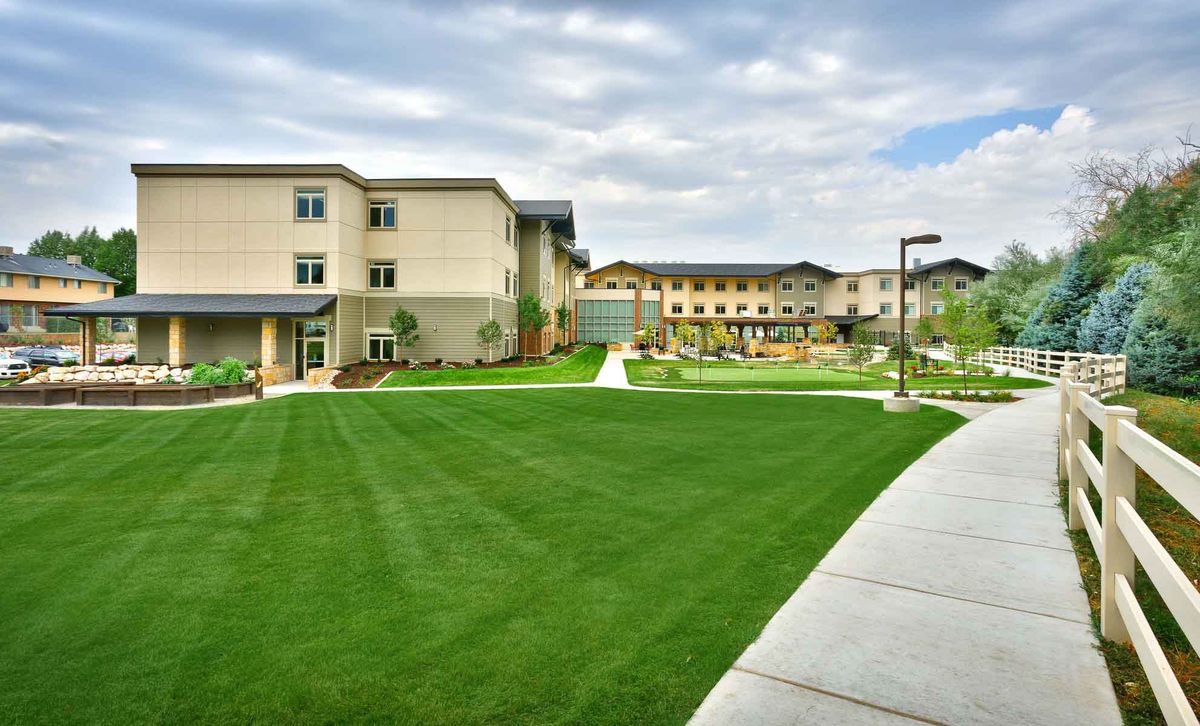 A modern building with a well-maintained lawn and sidewalks, under a cloudy sky.