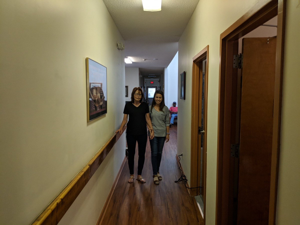 Two people walking down a hallway inside a building.