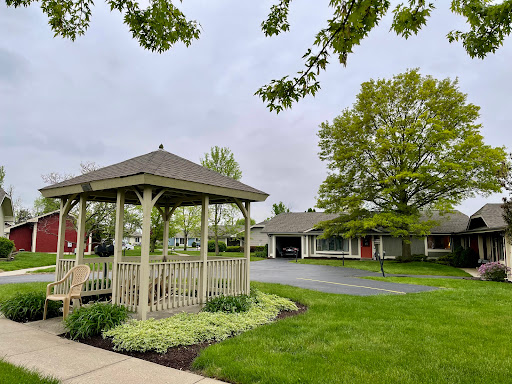 A serene outdoor space featuring a gazebo surrounded by lush greenery and suburban homes.