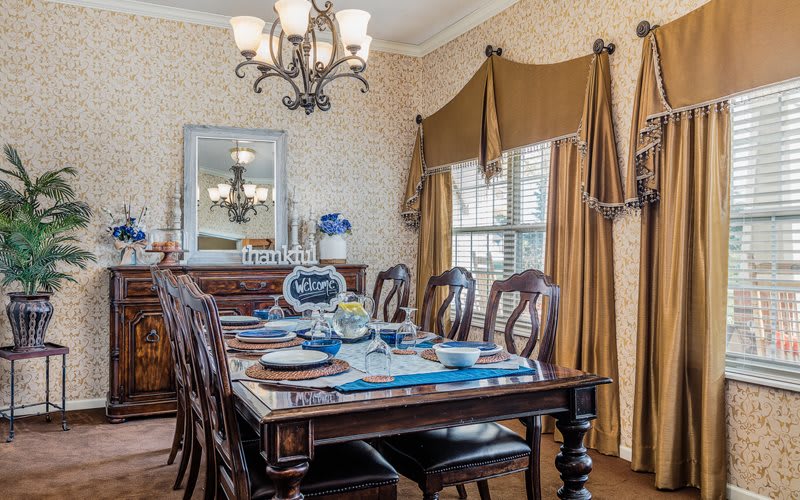 A traditional dining room with a set table, featuring elegant decor and a chandelier.