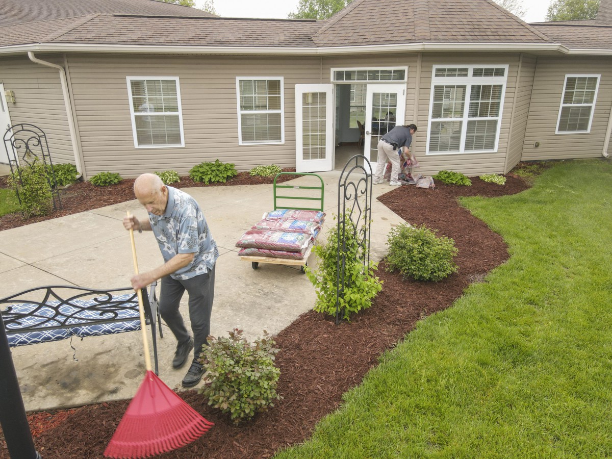 People working on landscaping and mulching in a garden patio area.