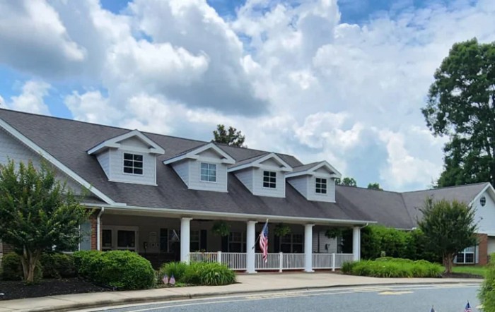A suburban-style house with a large porch under a cloudy sky.