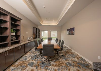 A modern conference room with a long table and chairs, featuring stylish office decor.