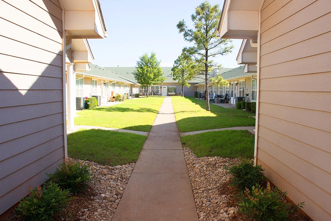 A sunny day at an apartment complex with a pathway and well-maintained lawns.
