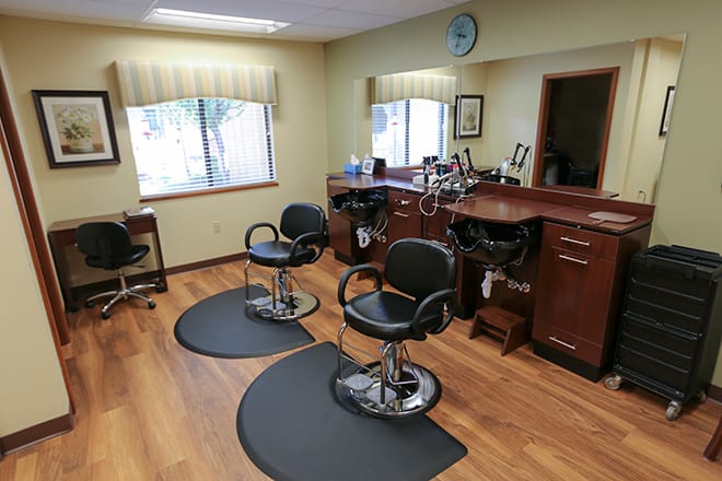 An interior view of an empty hair salon with two barber chairs and mirrors.