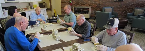 A group of seniors engaging in a crafting activity, assembling cube puzzles indoors.