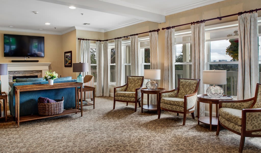 A well-lit living room with comfortable seating and large windows.