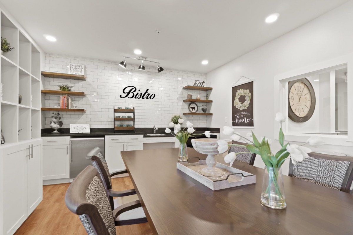 A modern kitchen and dining area featuring a wooden table, open shelves, and elegant decor.