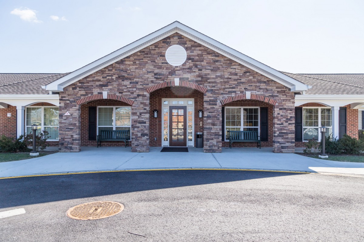 A brick building with a symmetrical design and a central entrance flanked by large windows.