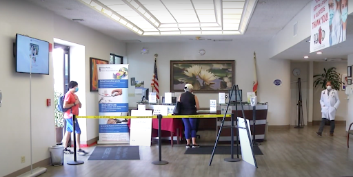 A woman standing at a counter in an office lobby, surrounded by informational signage and flags.