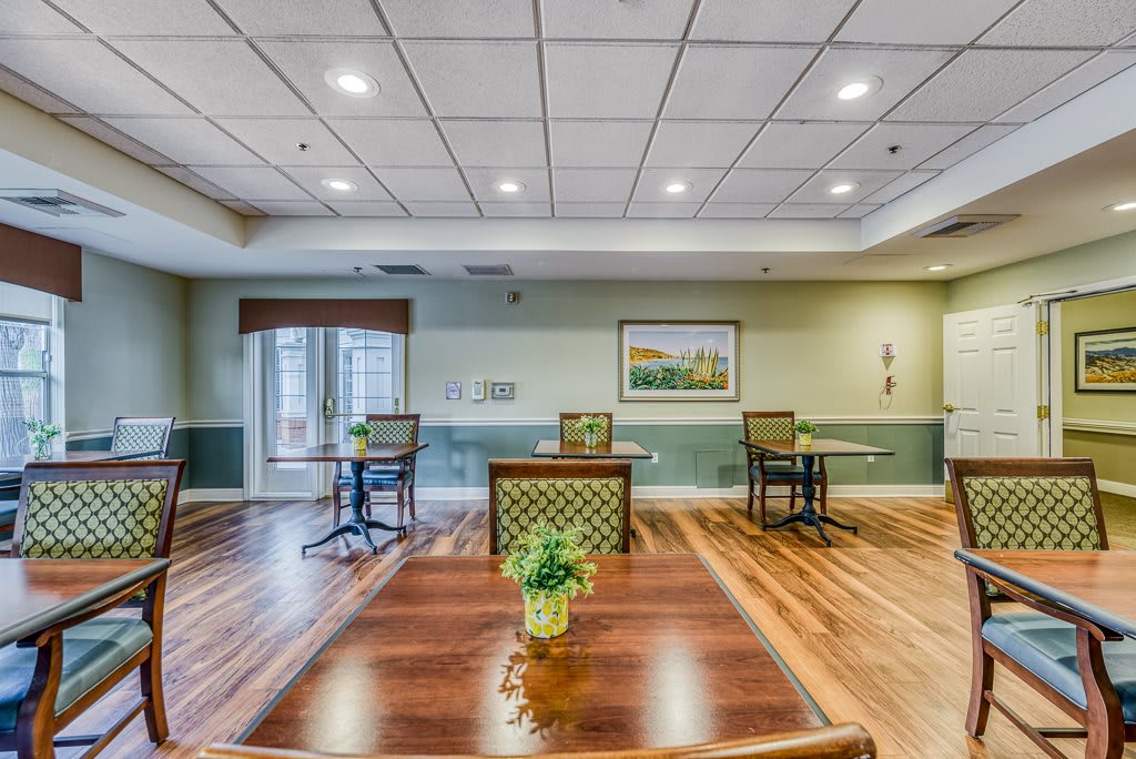A spacious interior room with wooden flooring, tables, and chairs arranged neatly.