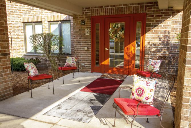 A cozy patio with red-accented seating and a stylish entrance.