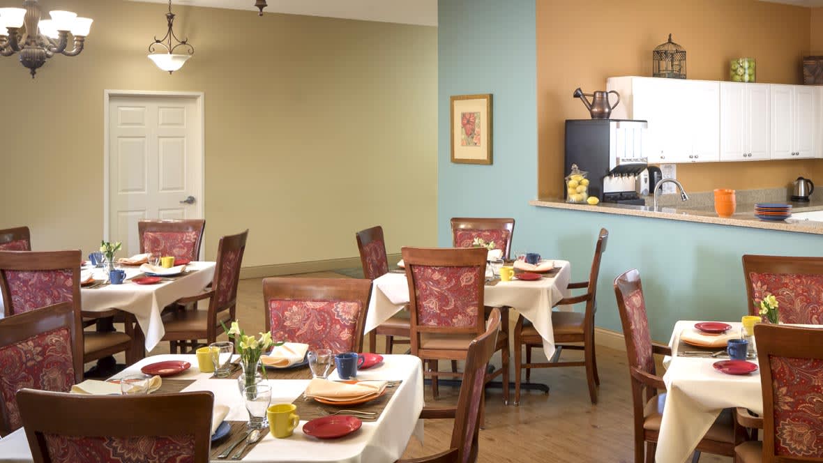 A cozy dining area with neatly set tables and comfortable chairs, featuring a warm interior design.