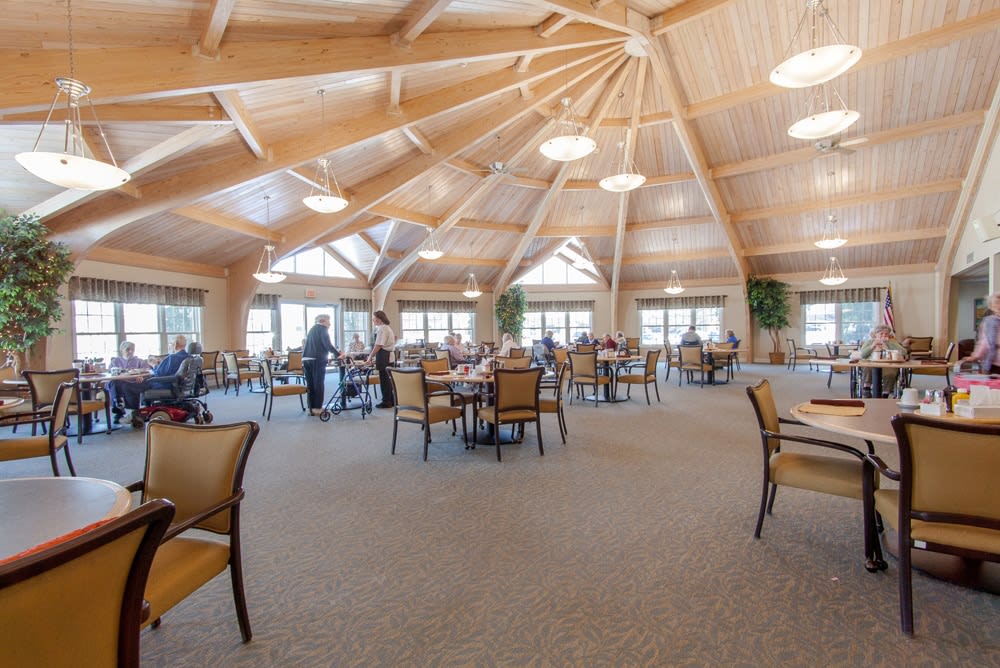 A spacious dining area with a wooden ceiling and modern furniture, featuring tables and chairs.