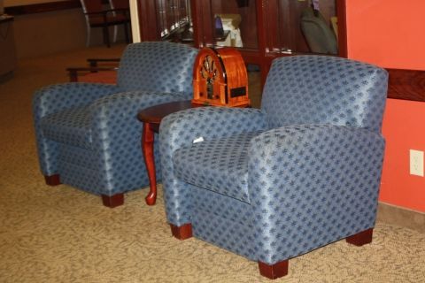 A pair of blue patterned armchairs positioned next to a small wooden table in a cozy indoor setting.