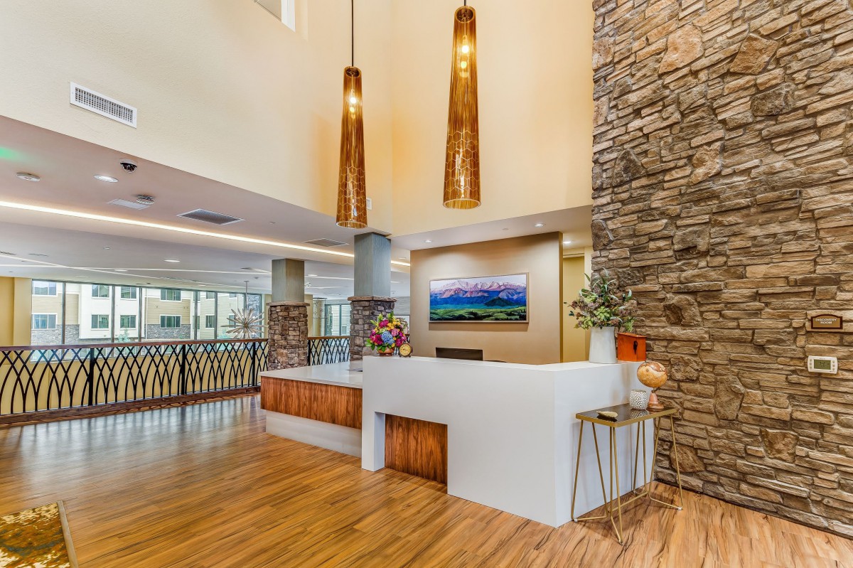 A modern reception area featuring wood flooring, decorative lighting, and a stone accent wall.