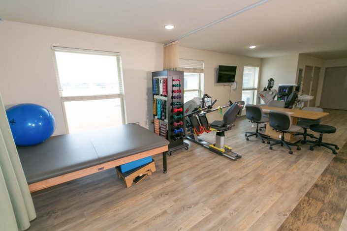 A well-equipped gym with a stationary bike, weights, and exercise mats.