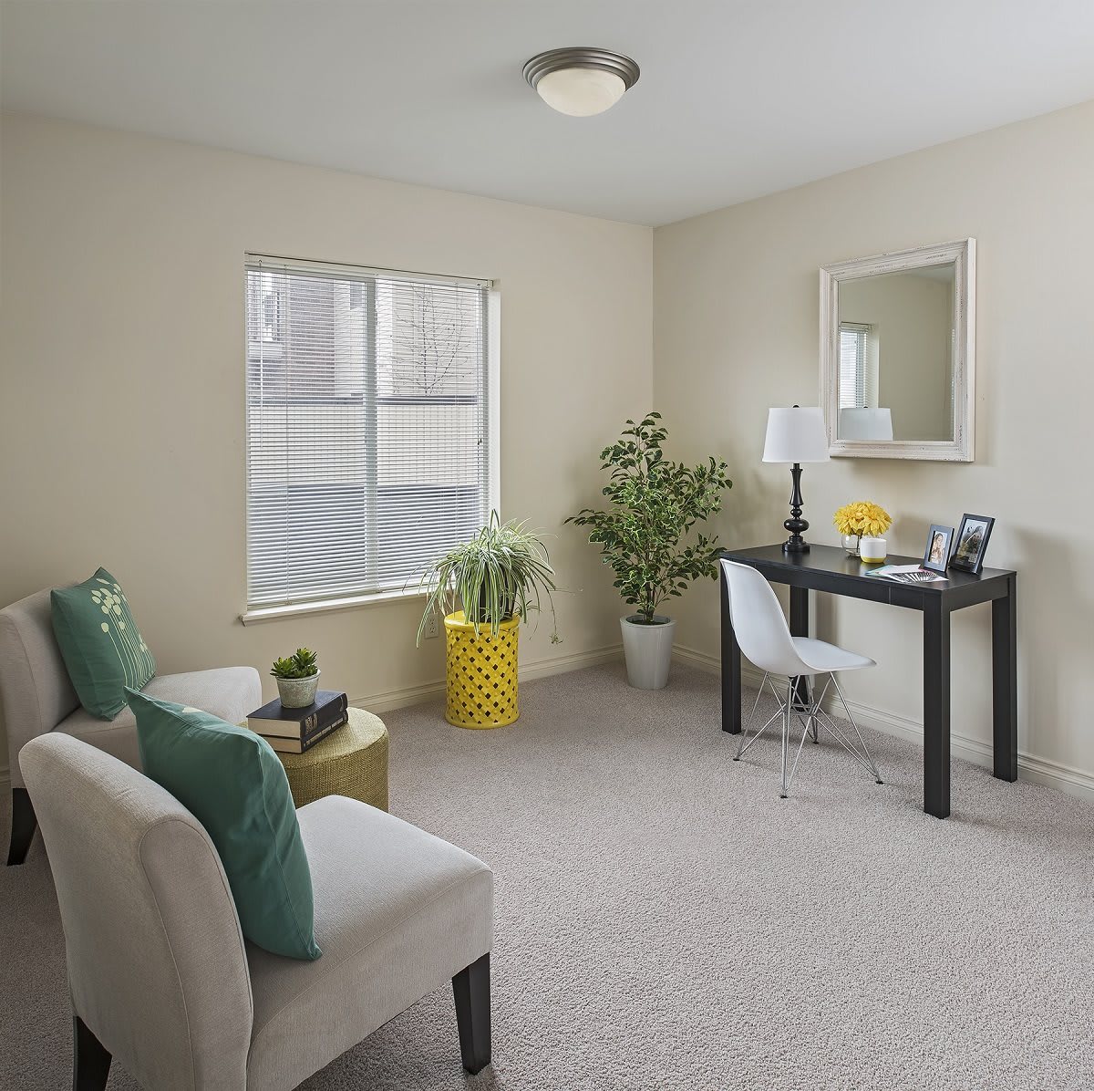 A cozy living room with a home office setup, featuring neutral tones and modern decor.